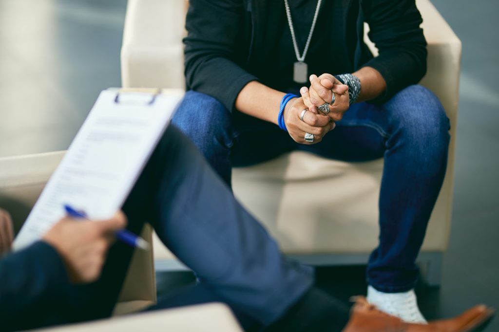Close-up of distressed black teenage boy having counselling with psychotherapist.
