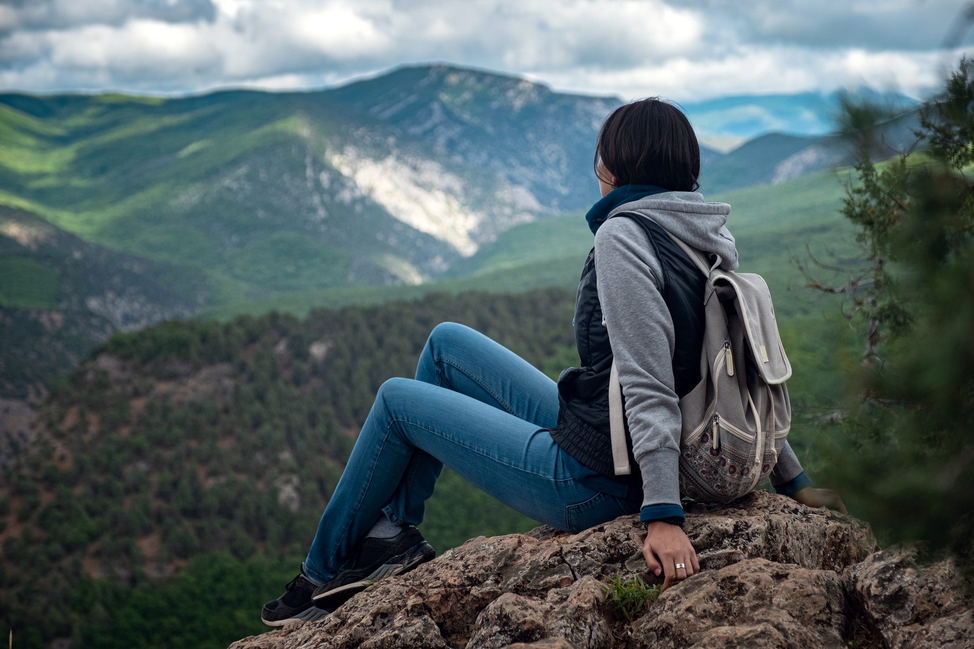 Young traveling woman on the top of the mountain cliff