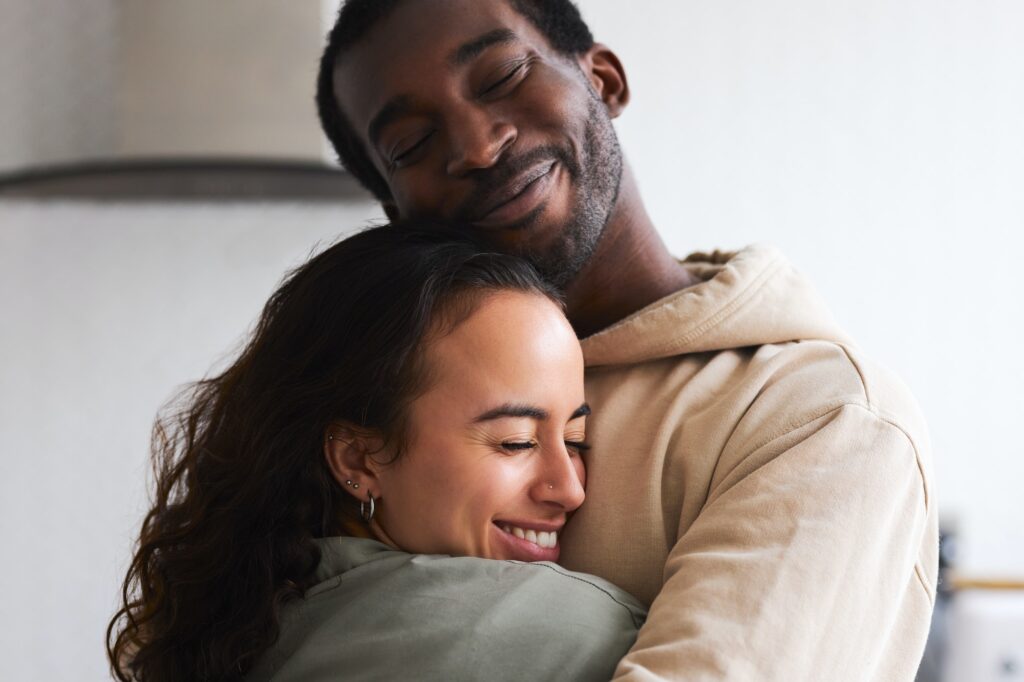 Loving Young Couple Hugging At Home Standing In Kitchen Together