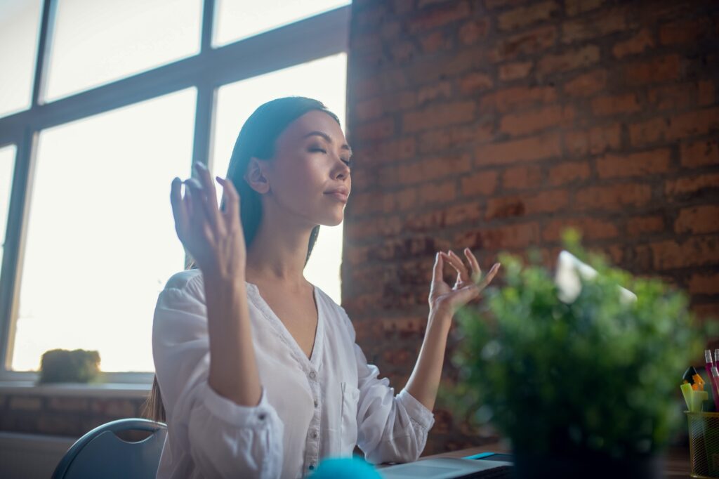 Beautiful calm young woman meditating at work