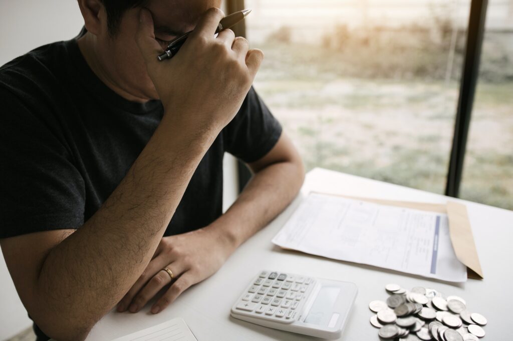 stressed about financial problems, with invoices and calculators