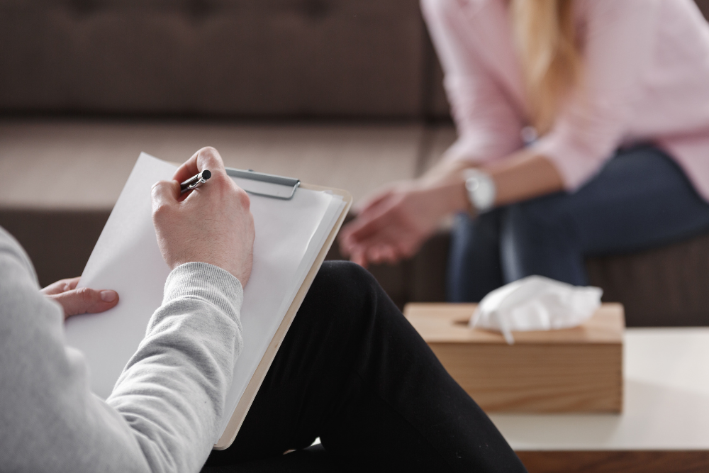 therapist writing on clipboard with patient in background