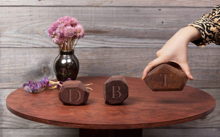 letters DBT written on blocks placed on wooden table
